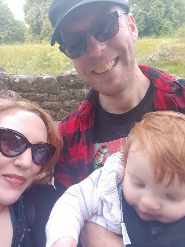 A photo of Nathan with his partner and their daughter smiling at the camera.