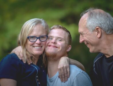 A mother, grown up son and dad all smiling in a garden