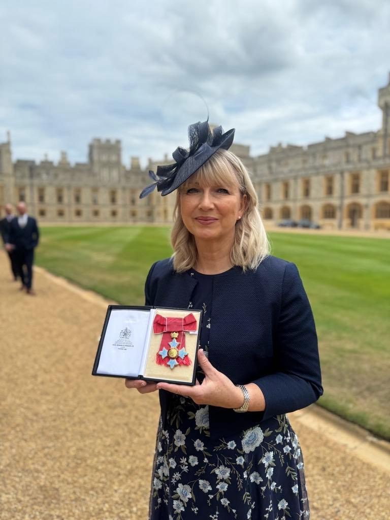 Family Fund CEO, Cheryl Ward, holding the CBE at Windsor Castle and smiling at the camera.