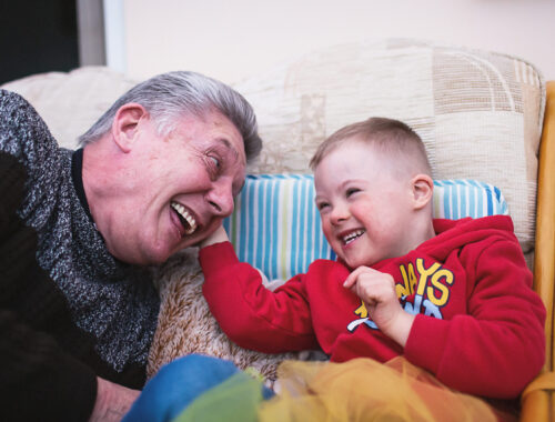 Adult and child smiling at each other on a sofa