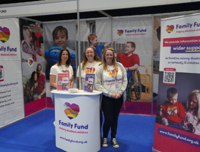 Three women standing around a Family Fund podium surrounded by Family Fund posters.