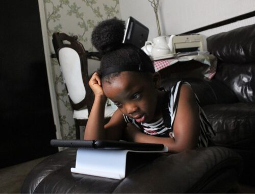 A little girl using a tablet on the sofa