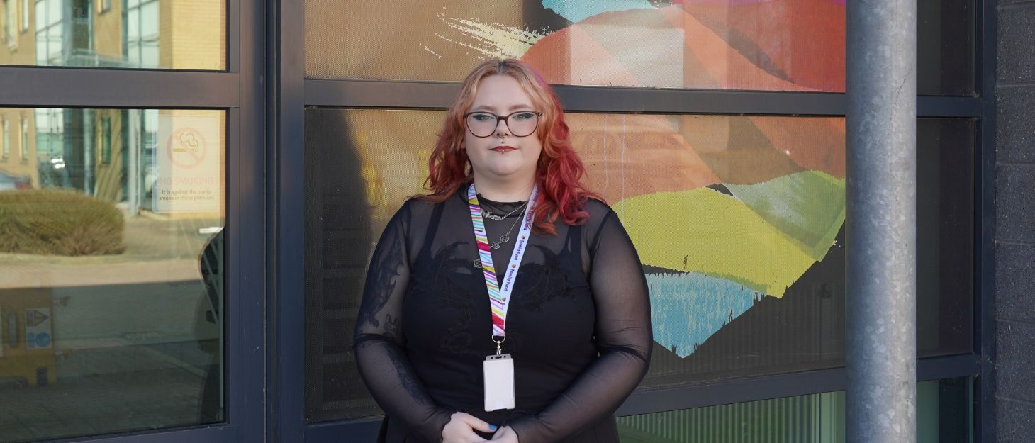 Grace, Family Fund supported intern, stands in front of the Family Fund logo at our HQ