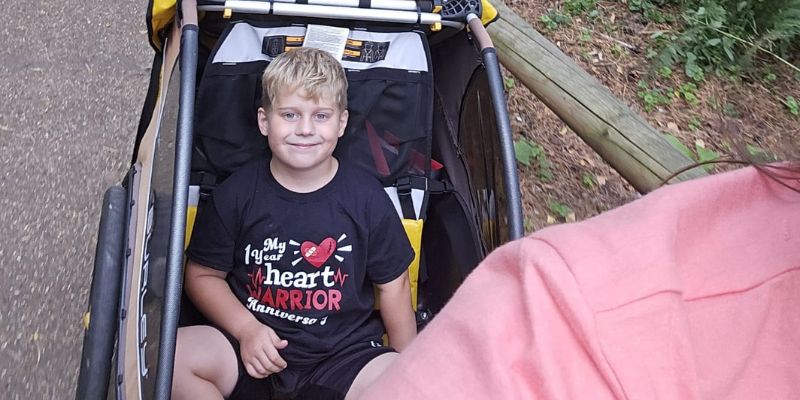 A little boy with blond hair in a bike trailer