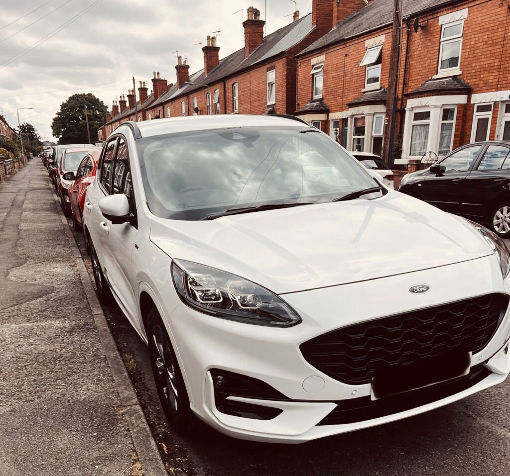 A white large car parked in the street