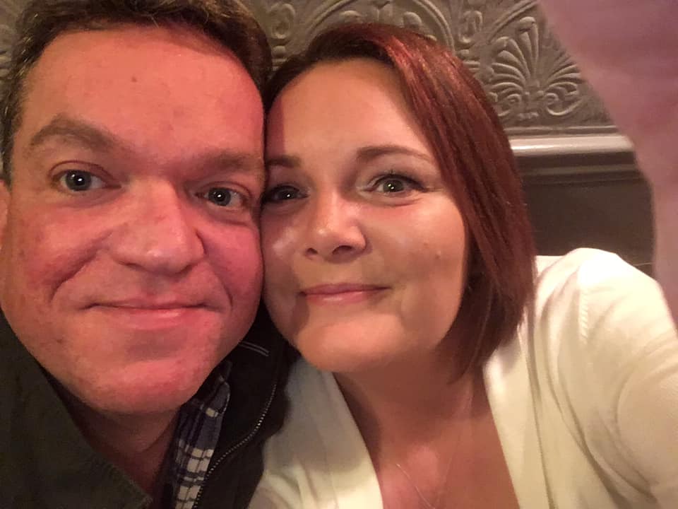 Couple smile at camera, taking selfie. 