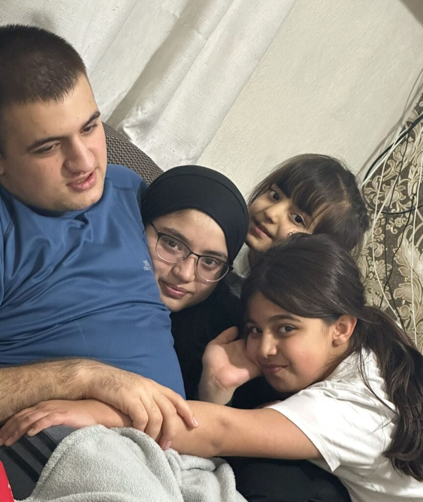 A group of four siblings sitting in a sofa together hugging