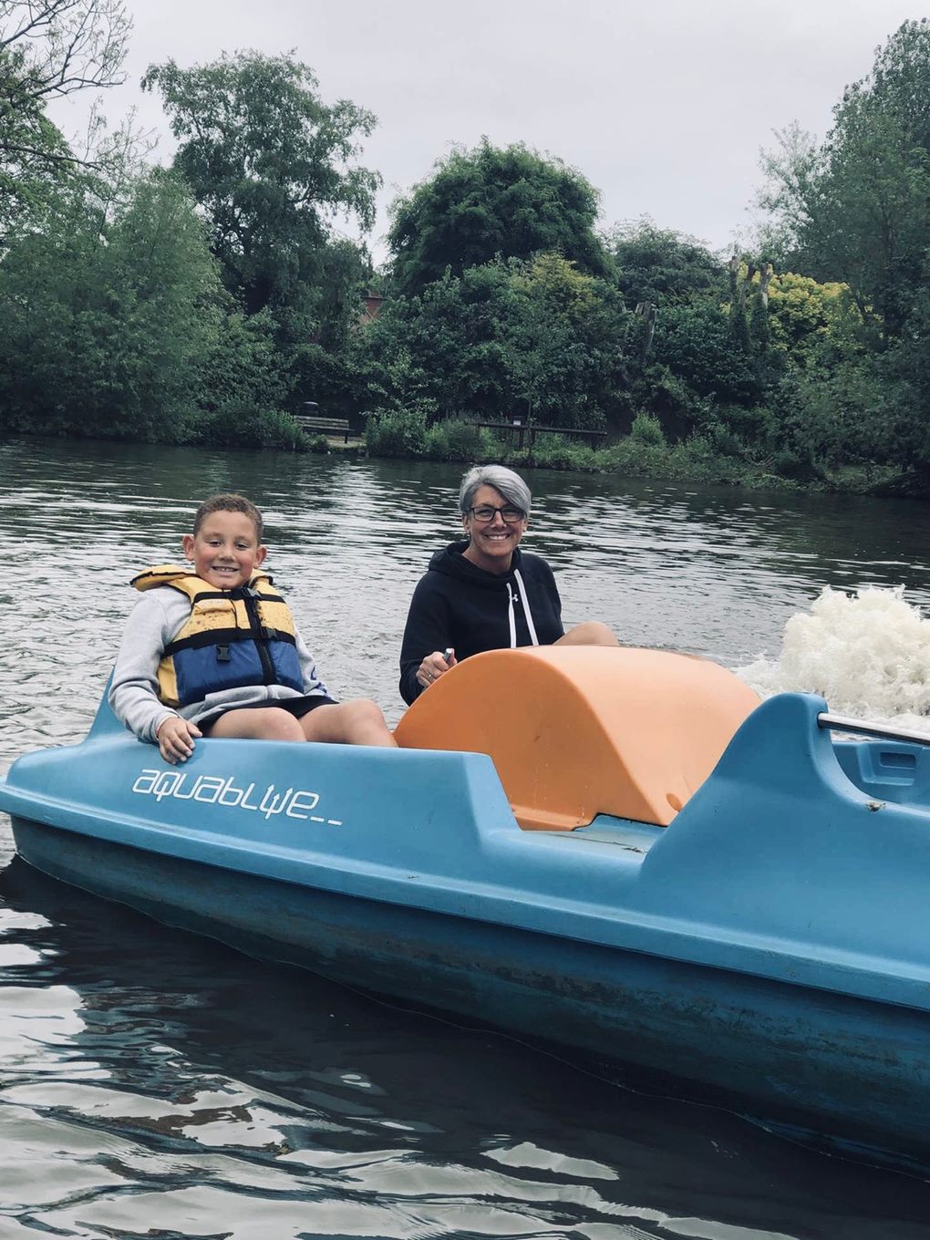 Mum and son wearing life jacket ride on a pedalo in the middle of a lake