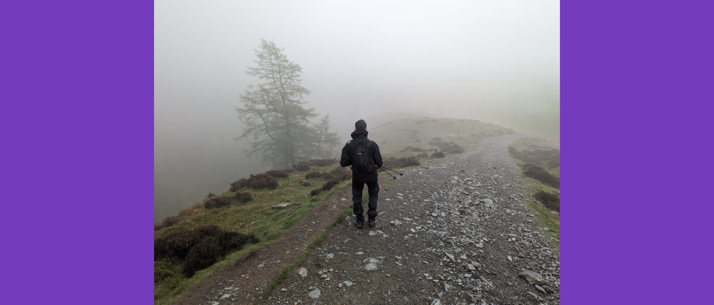 Man walking down a foggy mountainous path