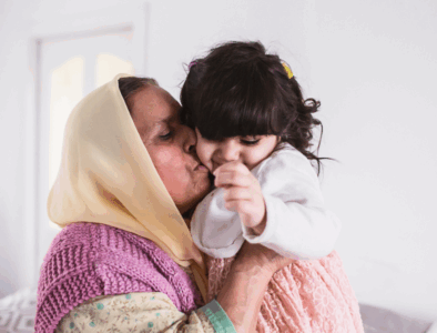 A woman is holding a little girl and giving her a kiss on the cheek.