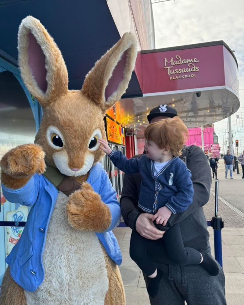 Matthew is holding Theodore who is touching a giant Peter Rabbit on holiday in Blackpool.