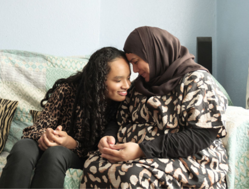 a mum and her daughter hugging and smiling at each other on a sofa