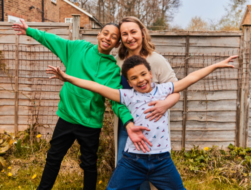 a mum hugging her two boys waving in their garden