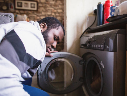 a young man loading the washer with clothes