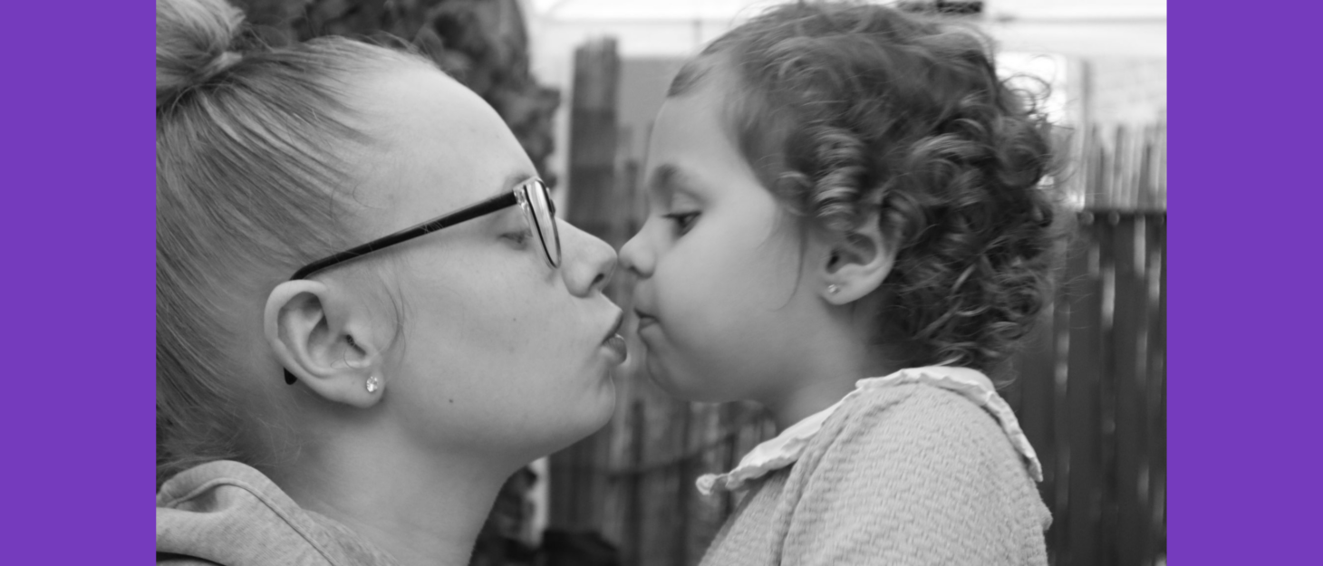 Lauryn and Amelia are facing one another, about to kiss. They are in the garden, and the image is in black and white.