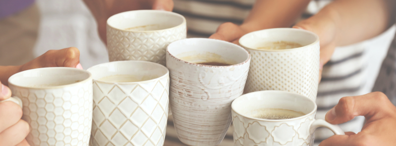 Coffee mugs being clinked together in celebration at a coffee morning