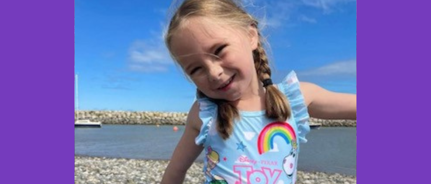 Girl wearing swimming costume smiles and poses on beach