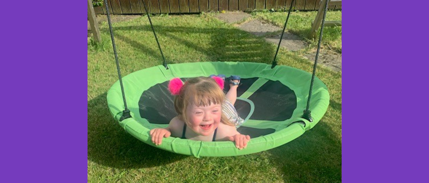 Young girl lies on round swing, grinning