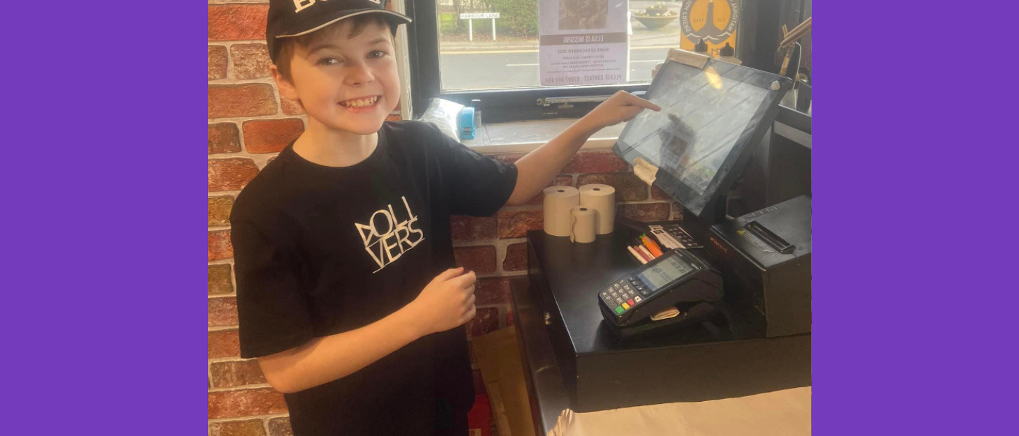Boy using shop till smiles at the camera