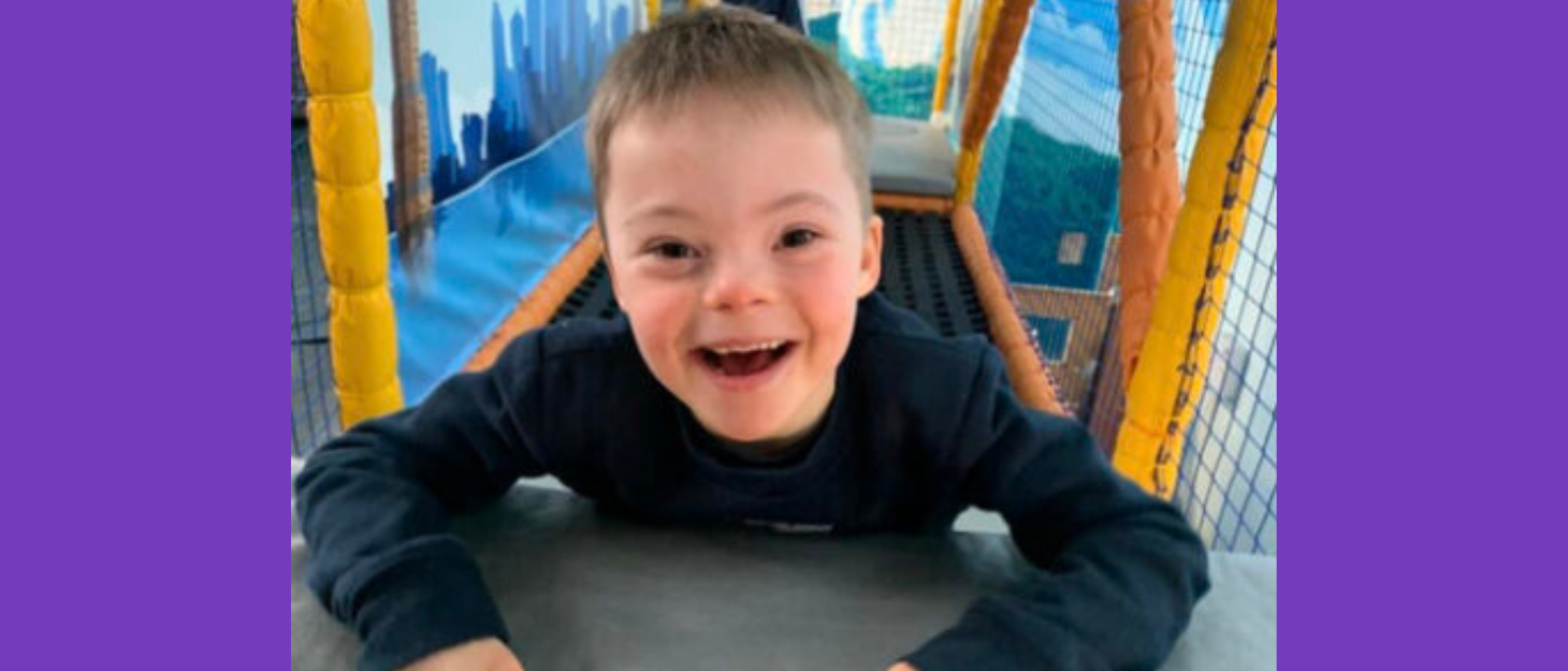 Little boy is in a soft play centre. He smiles at the camera.