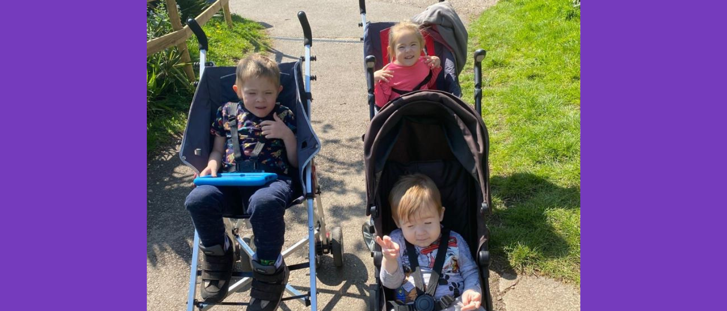 Three siblings (two brothers and a sister) sit in individual pushchairs.