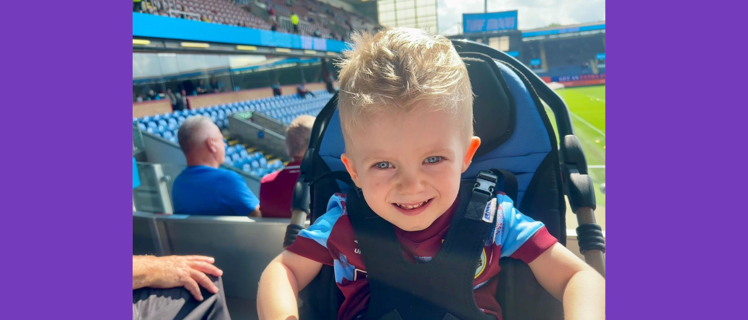A little boy in a wheelchair is in a football stadium