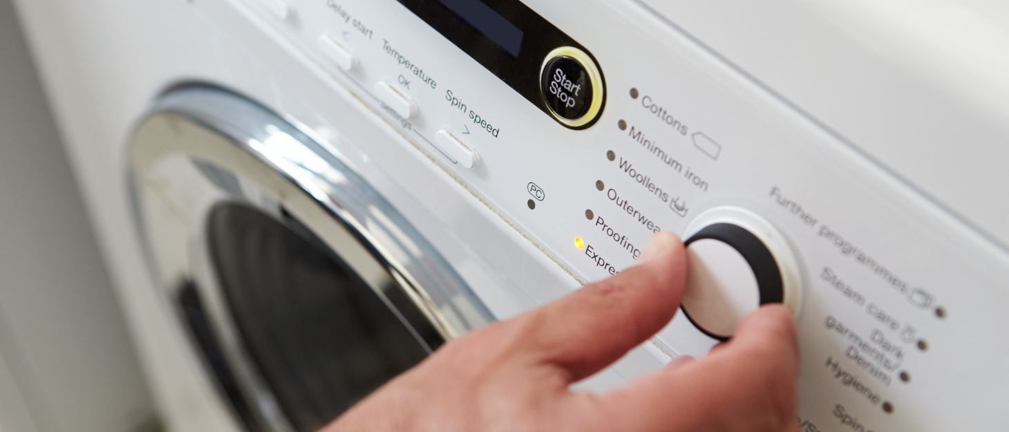 Someone touching a button on a washing machine