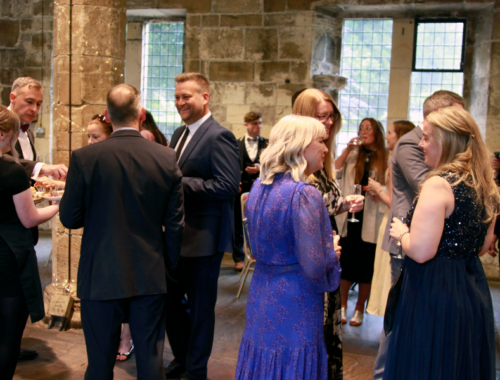 A group of people in evening dress are smiling and talking together