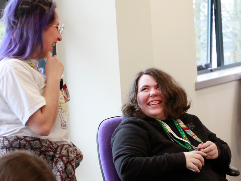 Colleagues, one of whom is wearing a Sunflower lanyard, chat to each other in the office.
