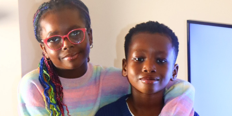 Elizabeth is standing with her arm around Testimony. They are both at home and are smiling.