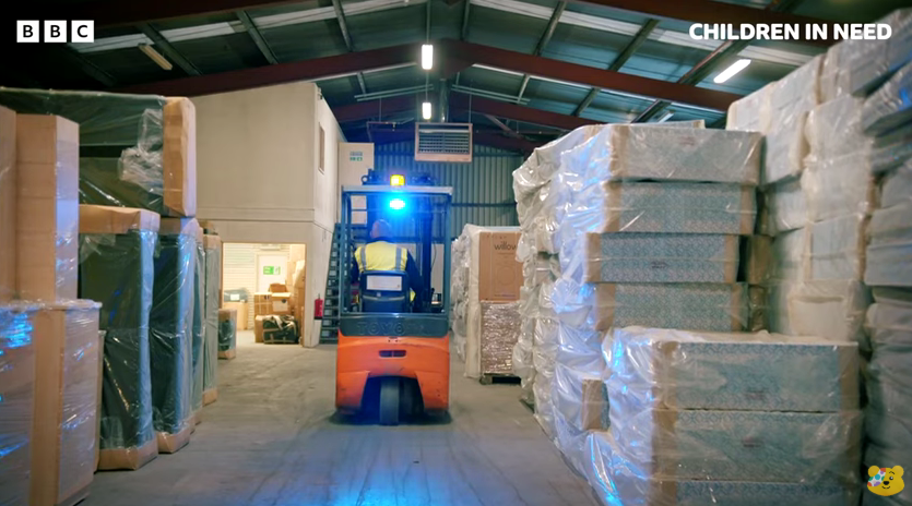 A forklift in a warehouse surrounded by mattresses