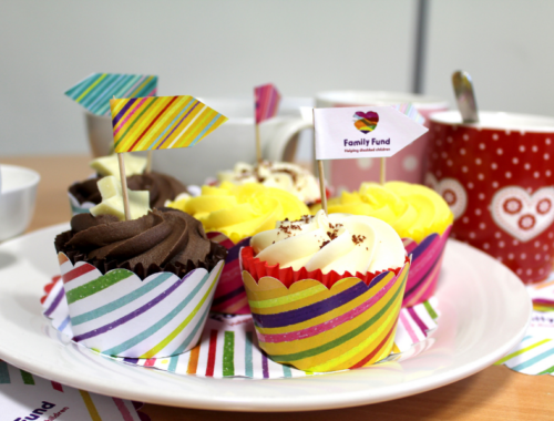 Frosted cupcakes displayed on colourful plates, with family fund flags in the top of them