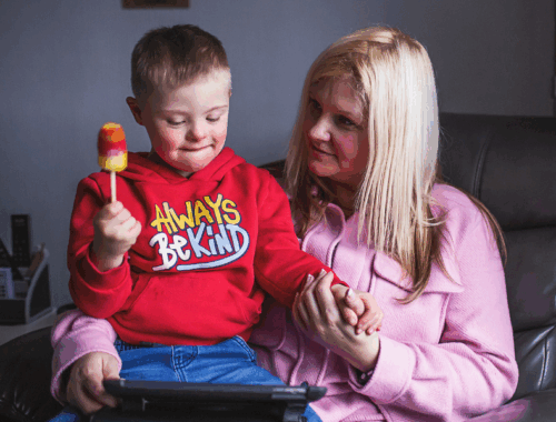 A mother is holding her child and her tablet.