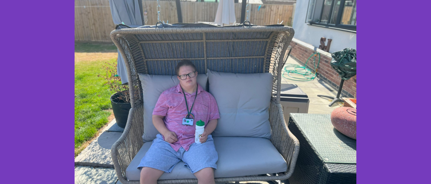 Young man sits on garden chair holding water bottle