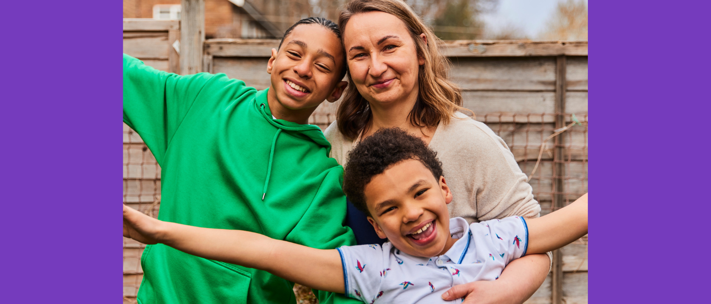Mum cuddles her two sons in the garden