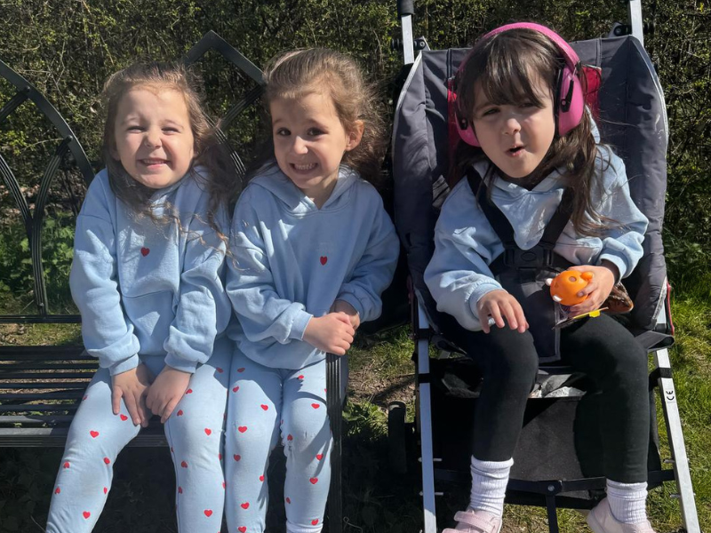 Five-year-old girl triplets sat together outside