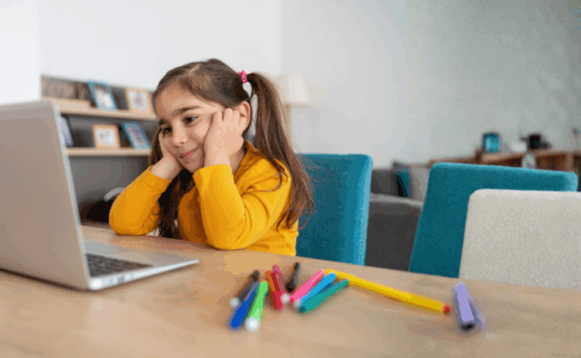 a young girl looking at a computer at a desk with a logo saying learning zone