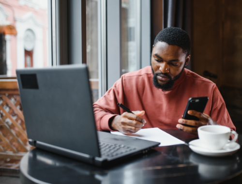 Man using computer and holding mobile phone