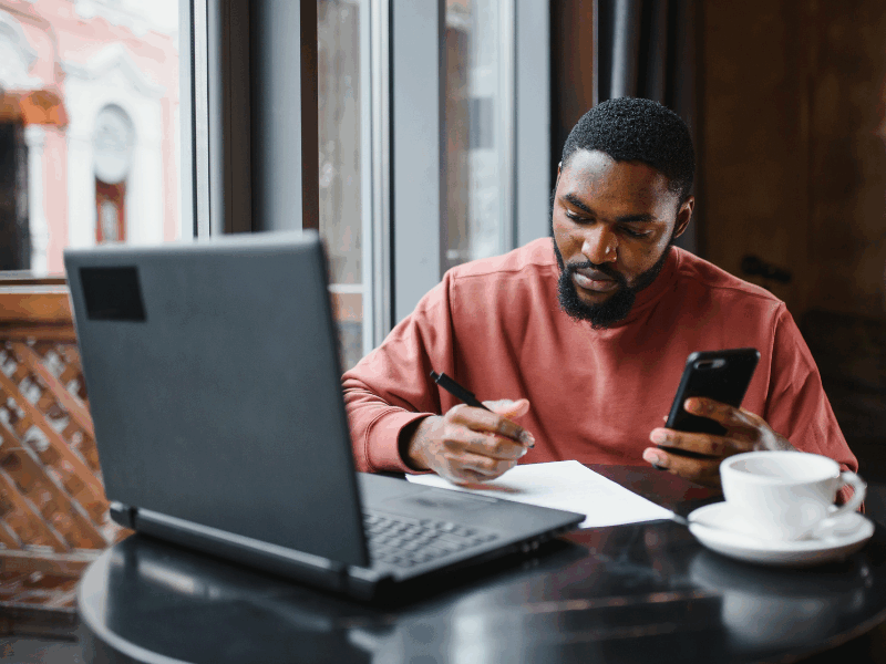 Man using computer and holding mobile phone