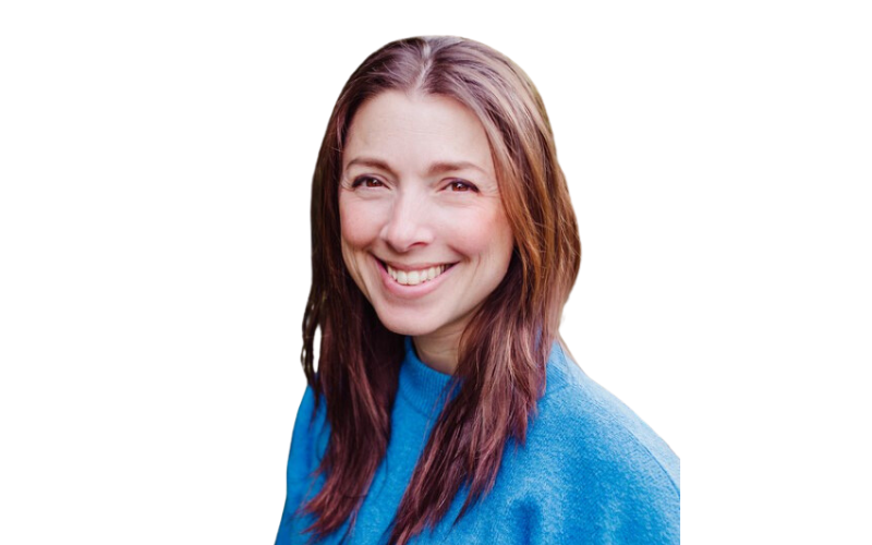 A lady with long brown hair wearing a blue jumper, smiling