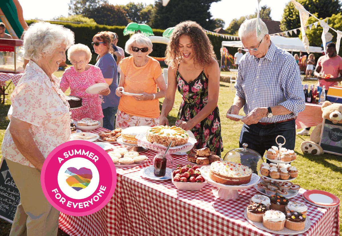 A group of people standing around a bake sale in the sun.