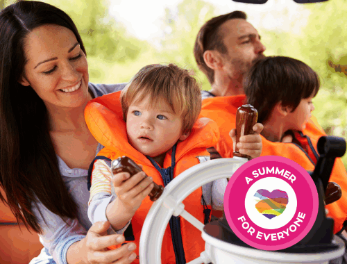 A family in lifejackets sitting together on a boat. A young child holds onto a boat wheel. A circular badge with a heart in the centre sits in the corner, surrounded by the text 'A summer for everyone.'