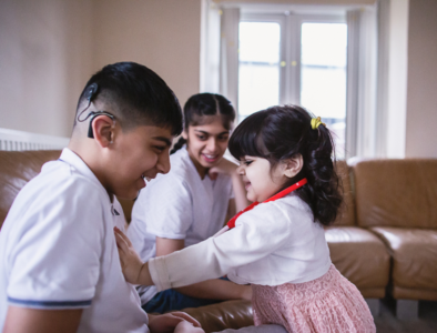 three siblings playing together on the sofa