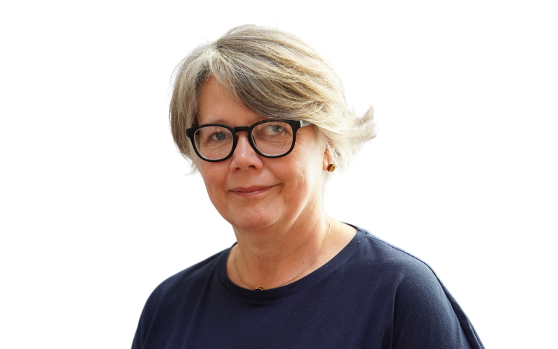 A woman with short hair wearing a navy top and dark framed glasses is smiling