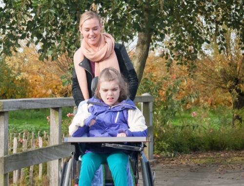 A young child in a wheelchair and her carer