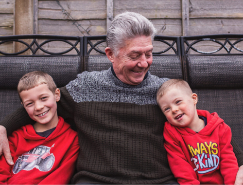 An man sat with arms around 2 younger children